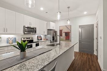 A kitchen with granite countertops and a grey door.